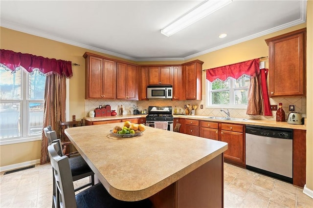 kitchen with a kitchen breakfast bar, sink, crown molding, tasteful backsplash, and stainless steel appliances