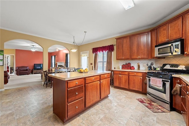 kitchen featuring appliances with stainless steel finishes, backsplash, ornamental molding, ceiling fan, and a kitchen island