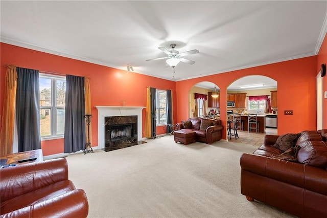 living room featuring light colored carpet, plenty of natural light, ornamental molding, and ceiling fan