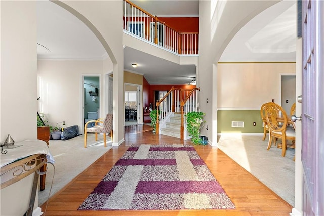 carpeted entryway featuring crown molding and a towering ceiling