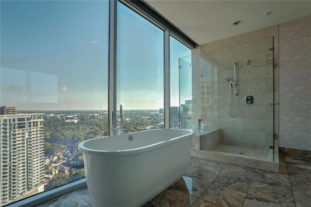 bathroom with shower with separate bathtub, a wealth of natural light, and floor to ceiling windows