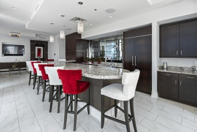 kitchen with hanging light fixtures, a kitchen island, paneled refrigerator, and dark brown cabinets