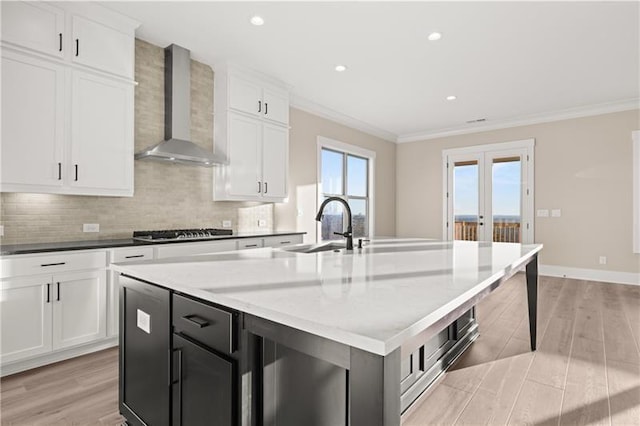 231 Laurel Vista Dr, Canton, GA 30114 - kitchen featuring wall chimney exhaust hood, stainless steel gas stovetop, crown molding, light wood finished floors, and an island with sink