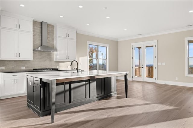 231 Laurel Vista Dr, Canton, GA 30114 - kitchen with wall chimney range hood, ornamental molding, light wood-style floors, tasteful backsplash, and a kitchen island with sink