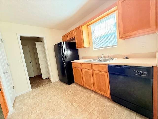 kitchen featuring baseboards, light countertops, a sink, and black appliances