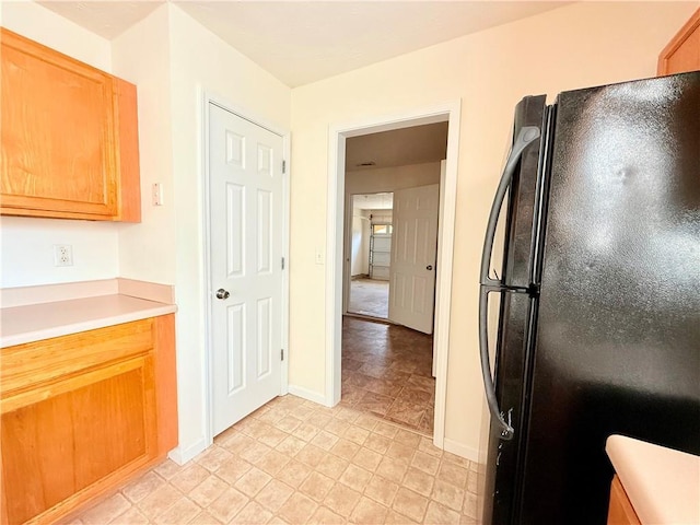 kitchen with freestanding refrigerator, light countertops, and baseboards