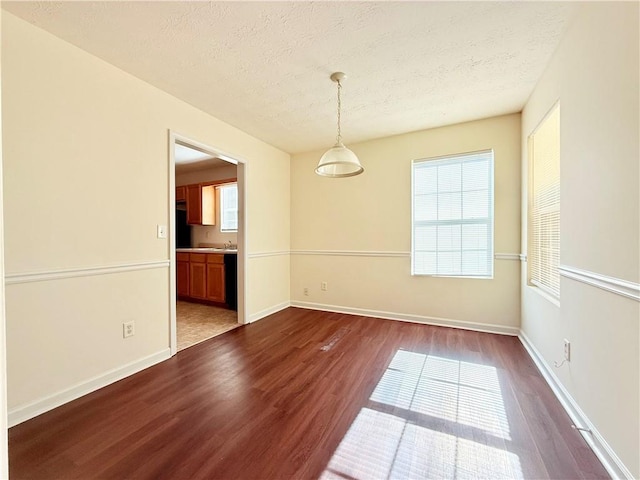 unfurnished room featuring dark wood-style floors, a textured ceiling, and baseboards