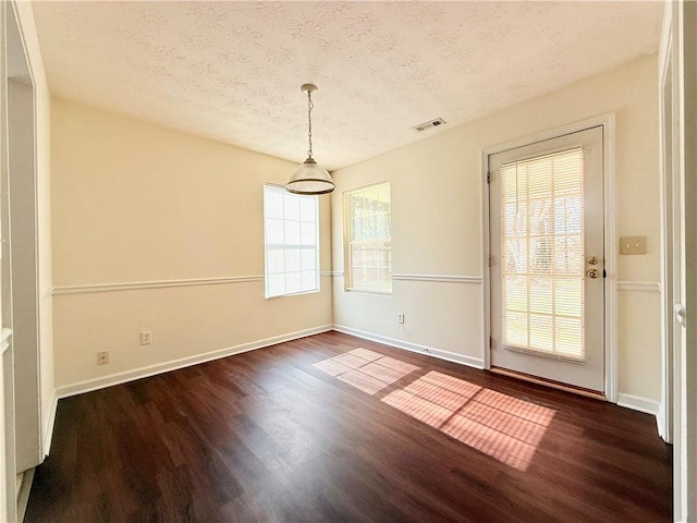 unfurnished room featuring visible vents, dark wood finished floors, a textured ceiling, and baseboards