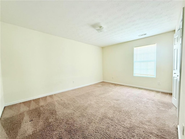 empty room with a textured ceiling, baseboards, visible vents, and light colored carpet