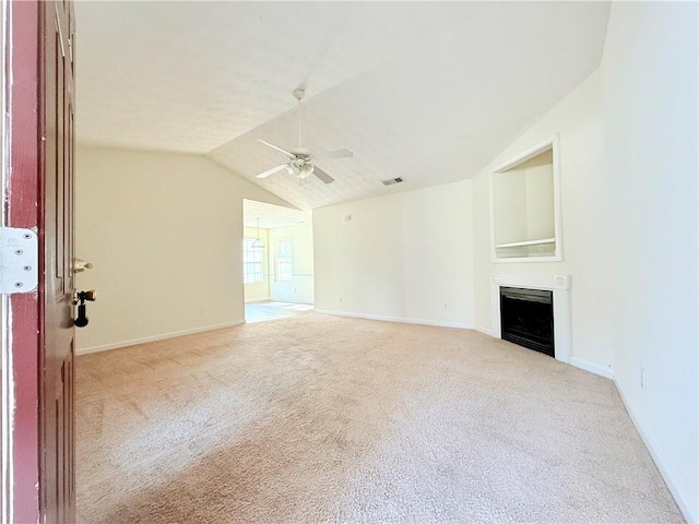 unfurnished living room featuring a fireplace, lofted ceiling, light colored carpet, visible vents, and a ceiling fan