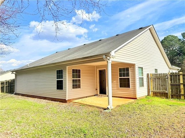 back of property with fence, a lawn, and a patio