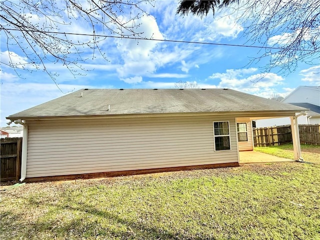 rear view of property with a patio, a shingled roof, a lawn, and fence