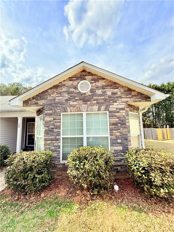 view of side of property with stone siding and fence