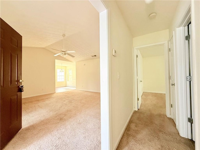 hall featuring light carpet, lofted ceiling, visible vents, and baseboards