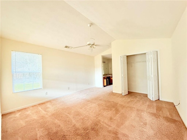 unfurnished bedroom featuring light carpet, visible vents, a ceiling fan, lofted ceiling, and a closet