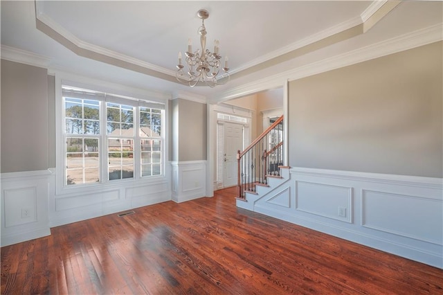 interior space with a tray ceiling, crown molding, dark wood-type flooring, and a chandelier