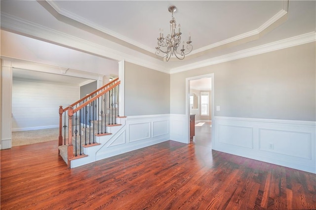 unfurnished room with a raised ceiling, ornamental molding, a notable chandelier, and dark hardwood / wood-style flooring