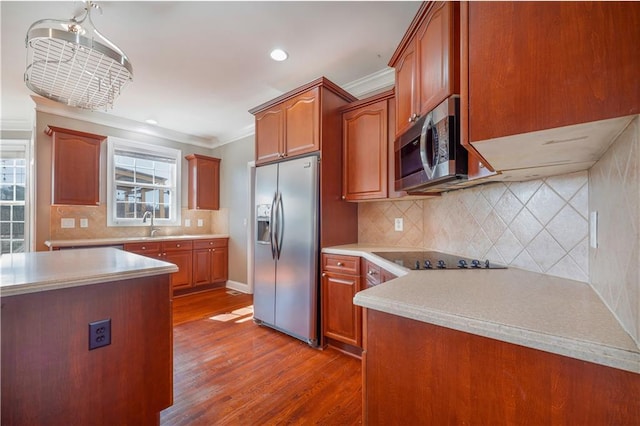 kitchen with a healthy amount of sunlight, ornamental molding, appliances with stainless steel finishes, and dark hardwood / wood-style flooring