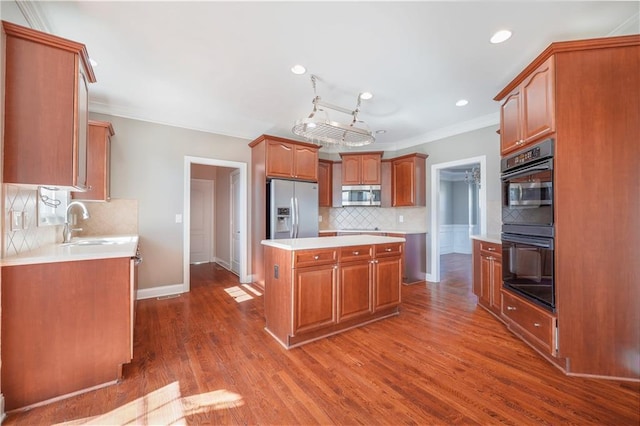 kitchen featuring sink, crown molding, appliances with stainless steel finishes, a center island, and dark hardwood / wood-style floors