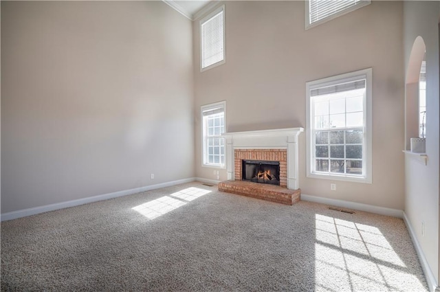 unfurnished living room featuring a healthy amount of sunlight, a fireplace, and carpet flooring