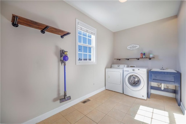 washroom with light tile patterned flooring, washer and clothes dryer, and sink