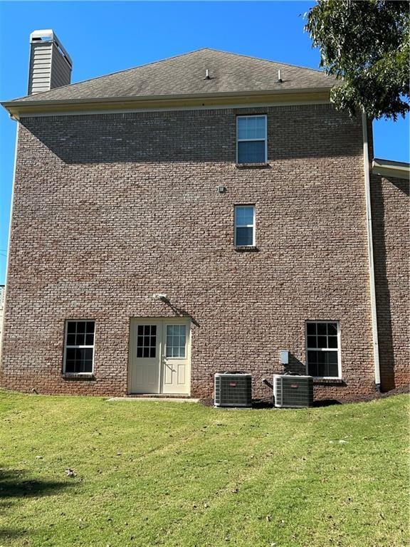 rear view of property with a yard and central AC unit