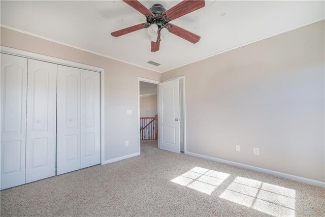 unfurnished bedroom featuring crown molding, a closet, ceiling fan, and carpet flooring