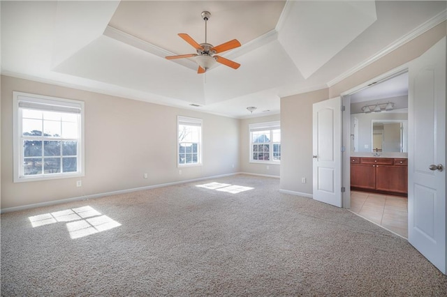 carpeted spare room with a raised ceiling, ornamental molding, and ceiling fan