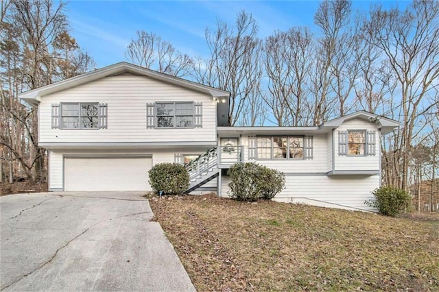 tri-level home with a garage, concrete driveway, and a front yard