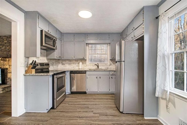 kitchen with stainless steel appliances, gray cabinets, light countertops, decorative backsplash, and wood finished floors