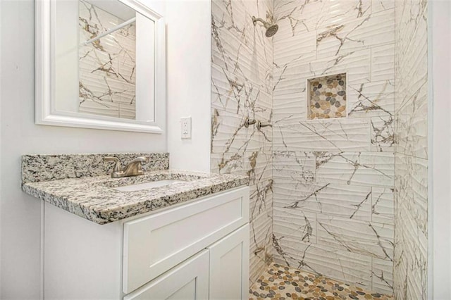 bathroom with a tile shower and vanity