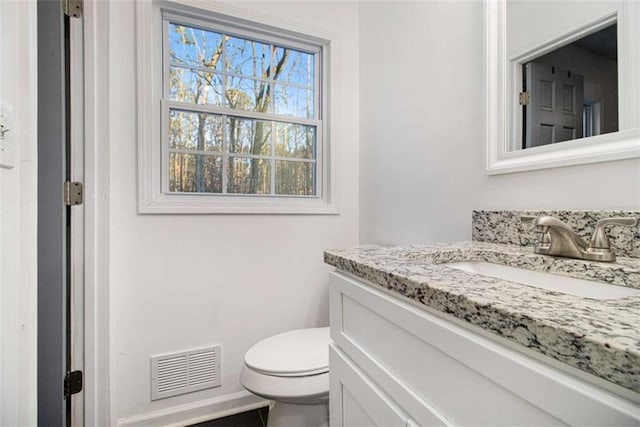 half bathroom with toilet, vanity, and visible vents