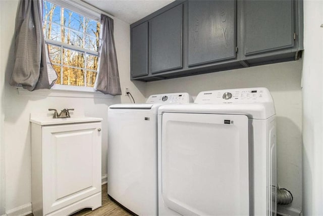 clothes washing area featuring separate washer and dryer and cabinet space