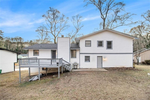 rear view of property featuring a deck, a yard, and a chimney