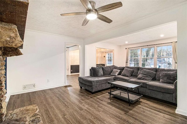 living area featuring dark wood-style floors, visible vents, ornamental molding, a textured ceiling, and baseboards