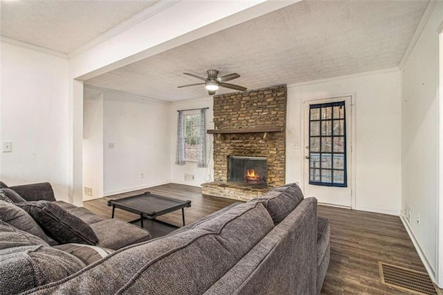 living room with dark wood-style floors, a fireplace, visible vents, and crown molding