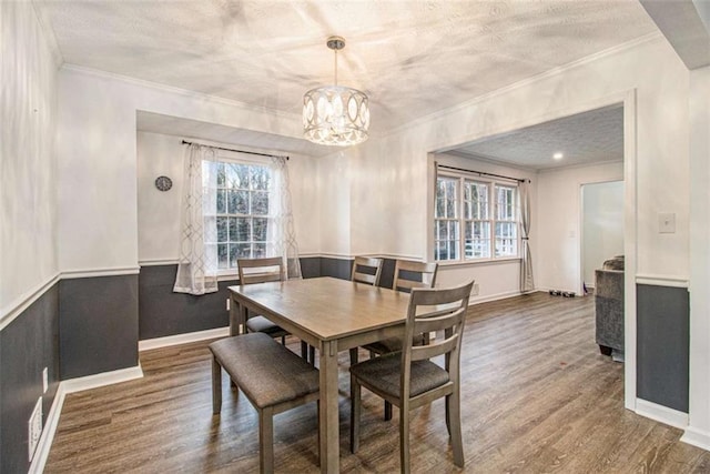 dining room with a textured ceiling, a notable chandelier, baseboards, ornamental molding, and dark wood-style floors