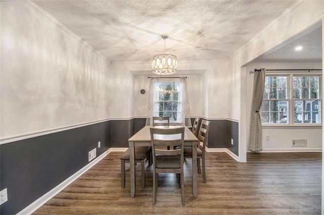 dining area featuring dark wood-style floors, visible vents, a chandelier, and a textured ceiling