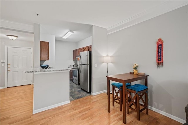 2700 Pine Tree Rd NE Unit 1214, Atlanta, GA 30324 - kitchen featuring light wood-style floors, crown molding, baseboards, brown cabinetry, and appliances with stainless steel finishes