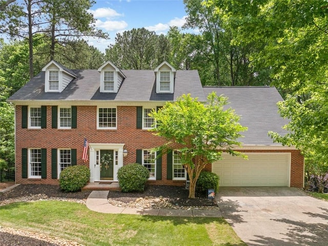 colonial inspired home with brick siding, an attached garage, and driveway