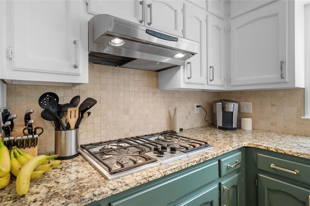 kitchen featuring under cabinet range hood, backsplash, white cabinets, and stainless steel gas stovetop