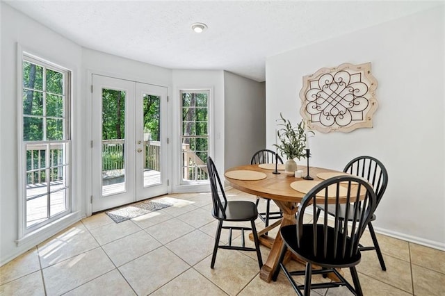 dining room with light tile patterned floors, a textured ceiling, a wealth of natural light, and french doors