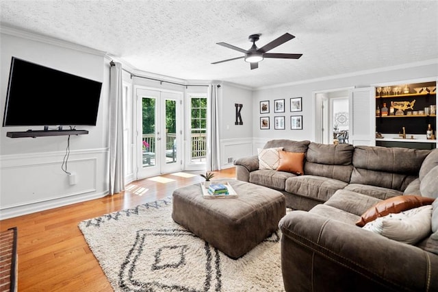 living room with ornamental molding, ceiling fan, and wood finished floors
