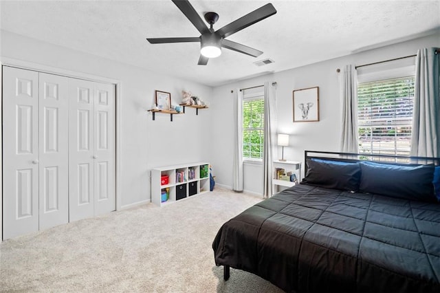 carpeted bedroom featuring a ceiling fan, a textured ceiling, visible vents, baseboards, and a closet
