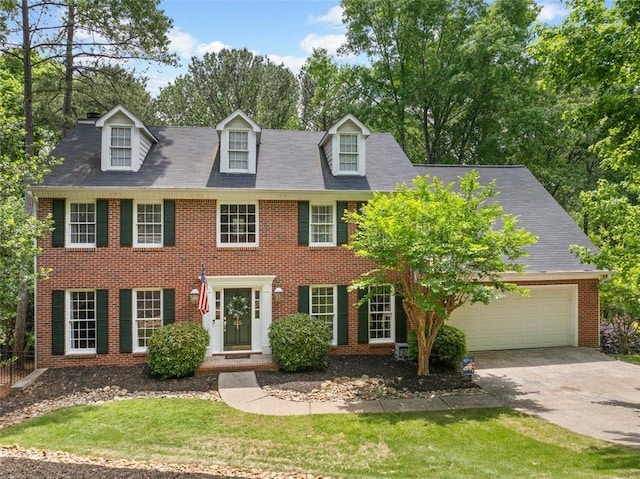 colonial inspired home with an attached garage, a front lawn, driveway, and brick siding