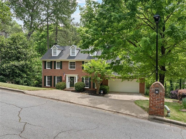 colonial inspired home featuring brick siding, a garage, and aphalt driveway