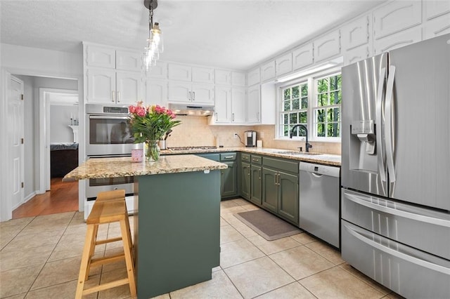 kitchen with appliances with stainless steel finishes, a sink, white cabinets, under cabinet range hood, and light tile patterned flooring