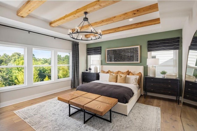 bedroom with beamed ceiling, wood-type flooring, and an inviting chandelier