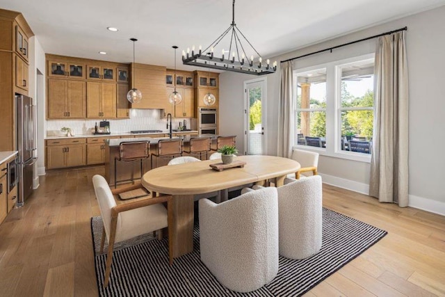 dining area with light hardwood / wood-style flooring and a notable chandelier