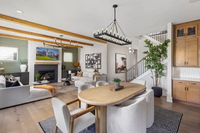 dining area with beamed ceiling, light hardwood / wood-style floors, and a notable chandelier